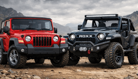 Two rugged SUVs, Thar and Thar Roxx, face off on a rocky terrain under a cloudy sky. Red Mahindra Thar next to black Thar Roxx SUV on rocky desert terrain